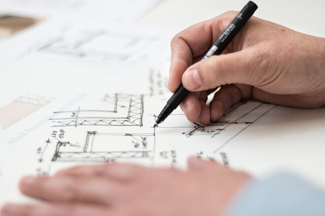 Architect holding a pen over a design of a building